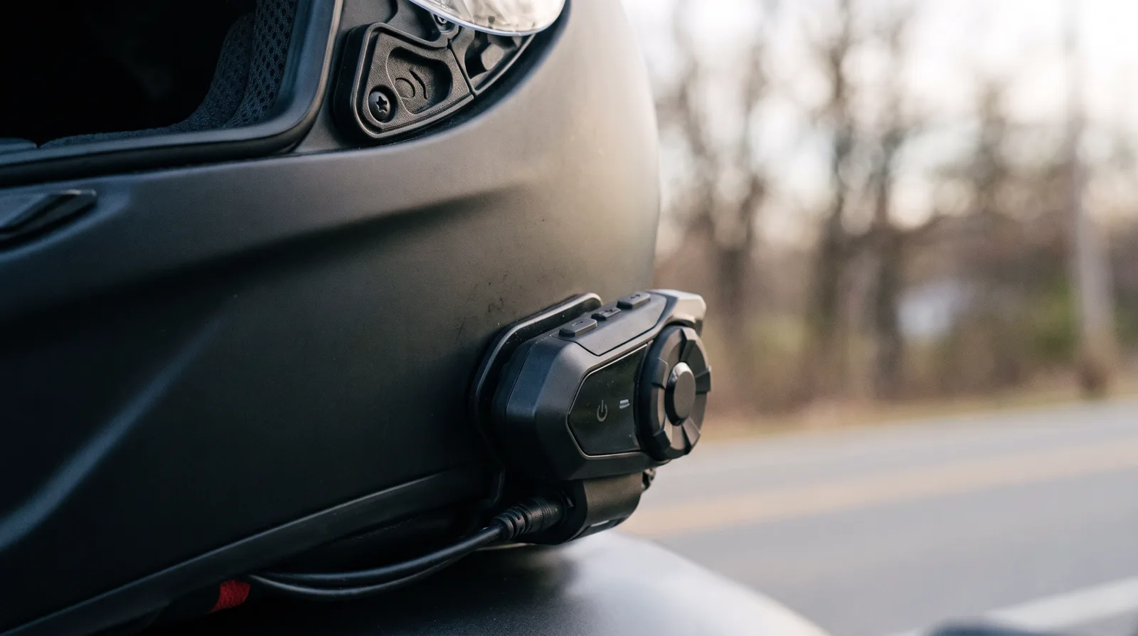 intercomunicador para capacete preto instalado na lateral de um capacete integral